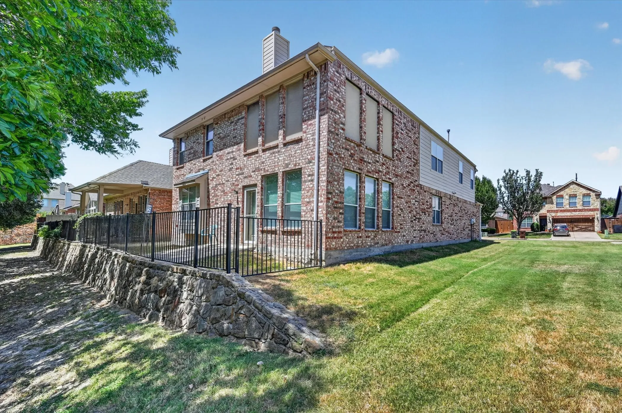Rear view of the home showcases the stone retaining wall and fabulous adjacent greenbelt, offering a beautiful natural backdrop.
