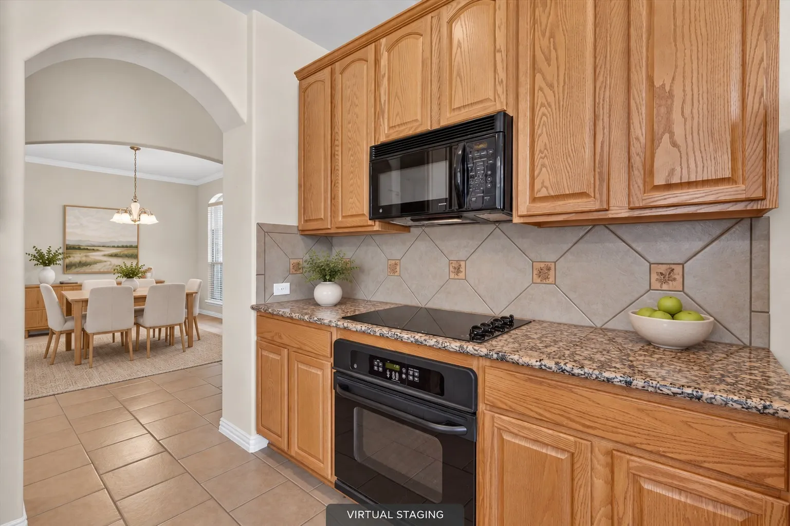 Built-in microwave & oven, flat cooktop, wood-finish cabinetry, patterned tile backsplash & granite countertops complete this well-appointed kitchen.