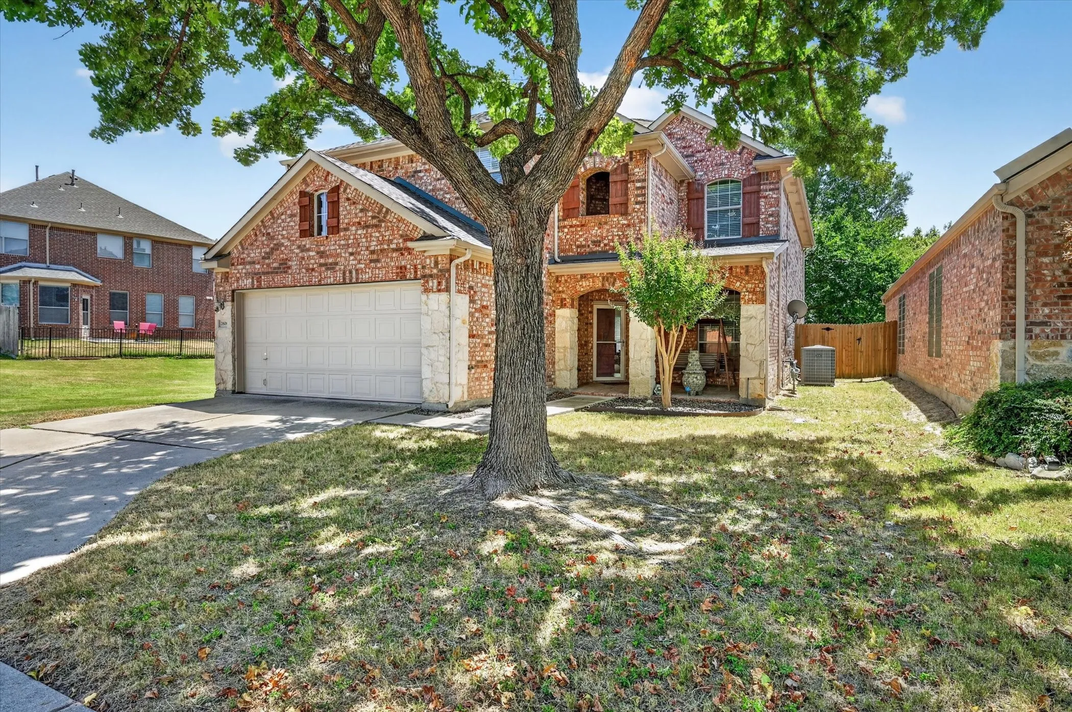 Beautiful brick exterior home with stone accents, mature shade trees, charming curb appeal, and a welcoming covered entry.