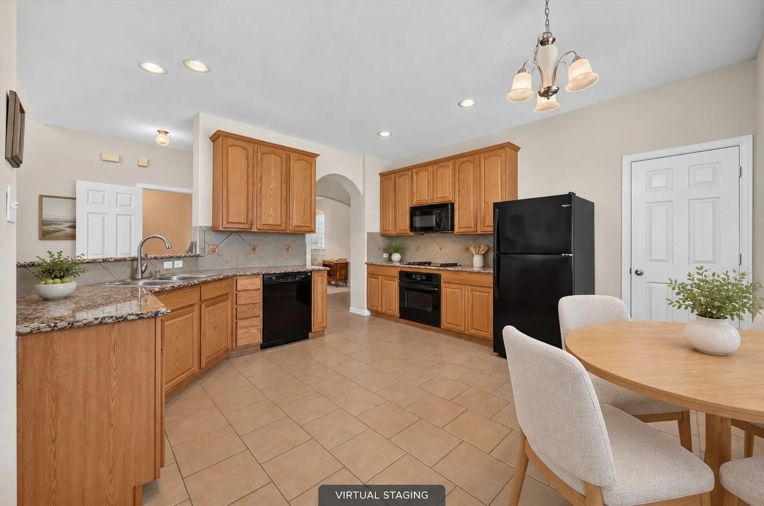 Another view of the spacious eat-in kitchen featuring neutral tones, black appliances & recessed lighting.