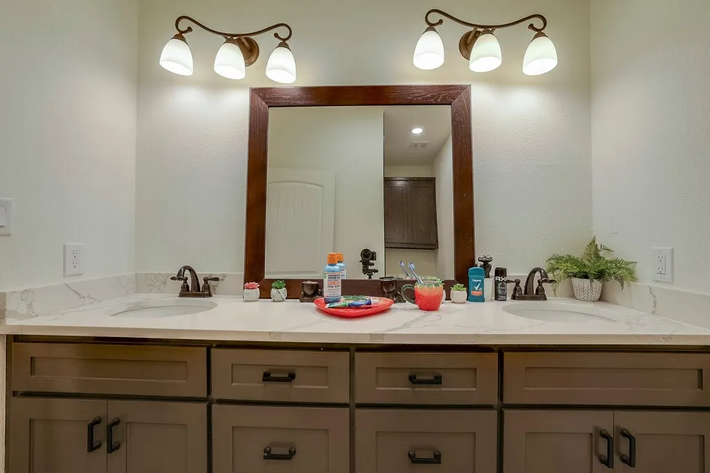 Dual vanity featuring undermount sinks, stone-finish countertops, warm wood-tone cabinetry, and bronze-finish fixtures
