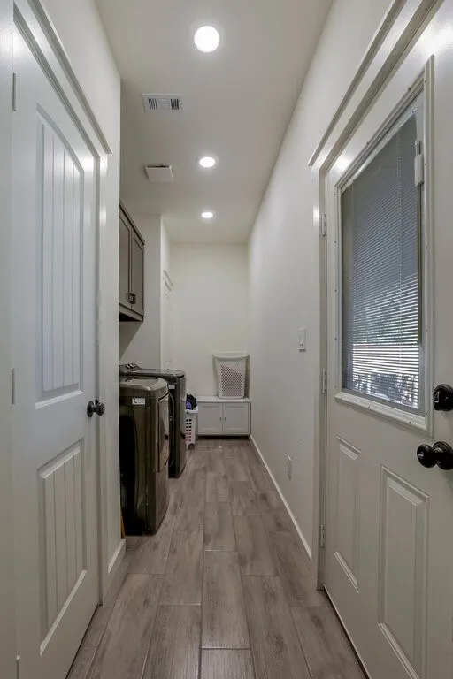 Laundry area featuring wood-finish tile flooring, recessed lighting, and upper cabinetry