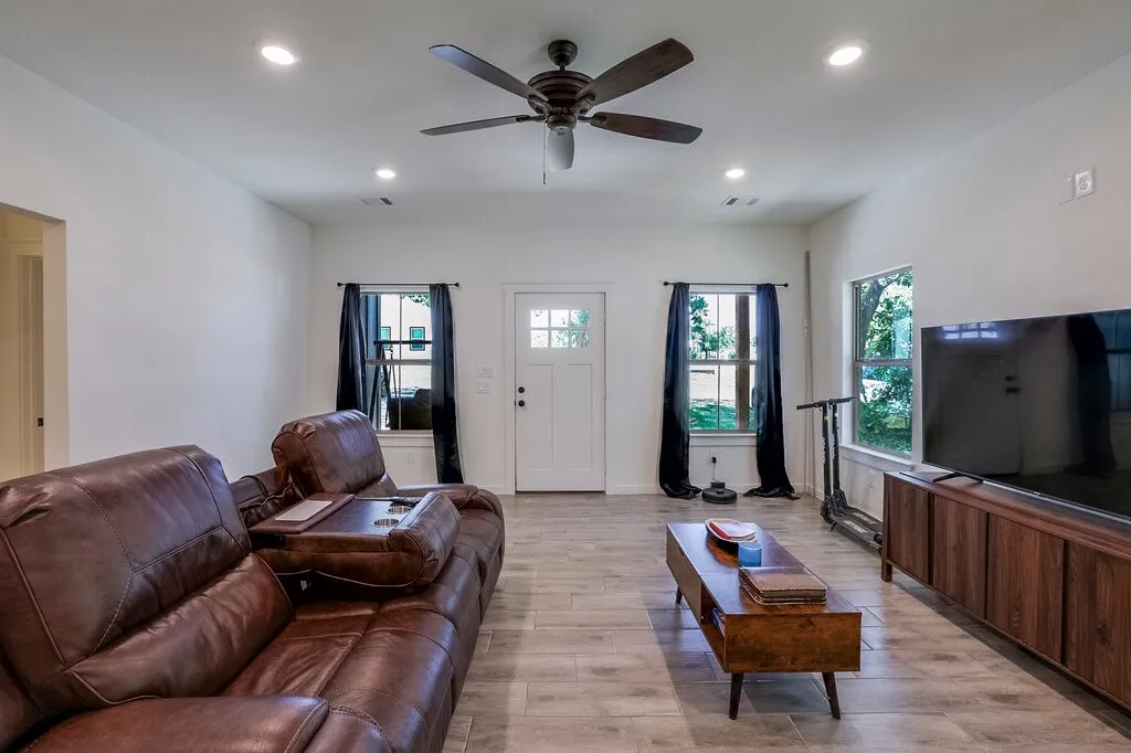 Living area with wood-finish flooring, recessed lighting, and a ceiling fan