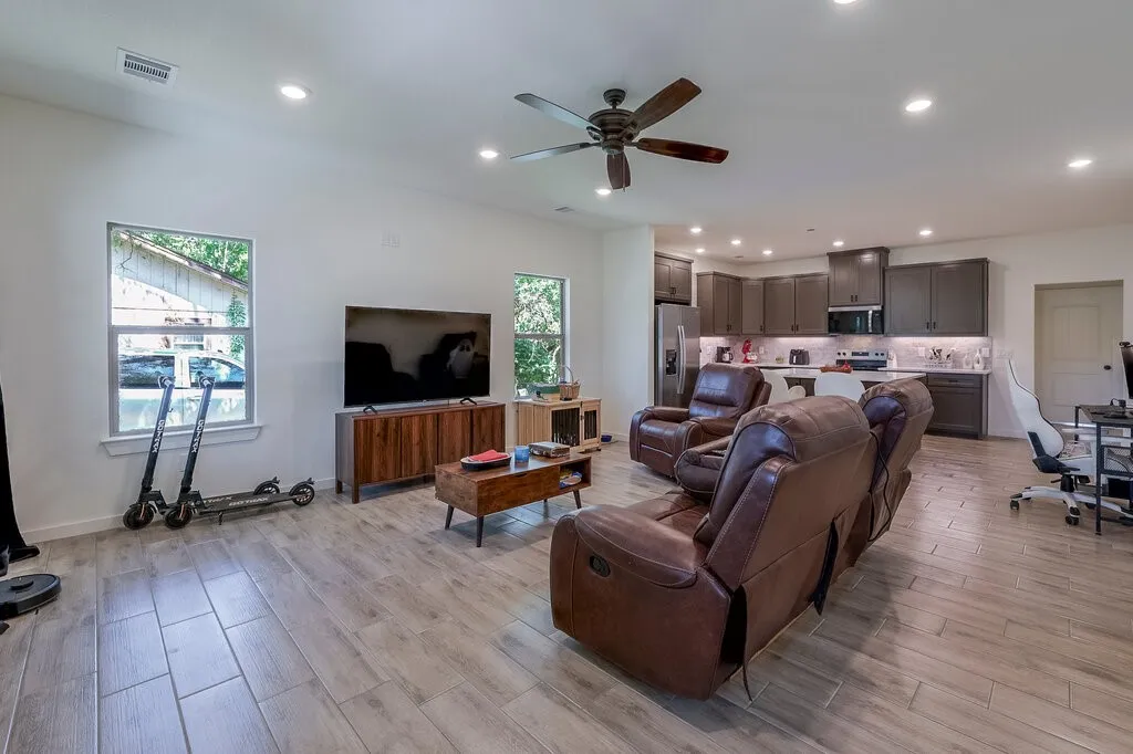 Open-concept living area featuring wood-finish tile flooring, recessed lighting, and a ceiling fan