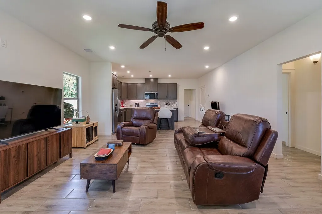Recessed lighting, wood-finish flooring, ceiling fan, open-concept layout, and modern cabinetry