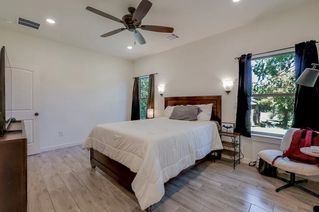 Bright interior with wood-finish flooring, a ceiling fan, recessed lighting, and wall-mounted sconces