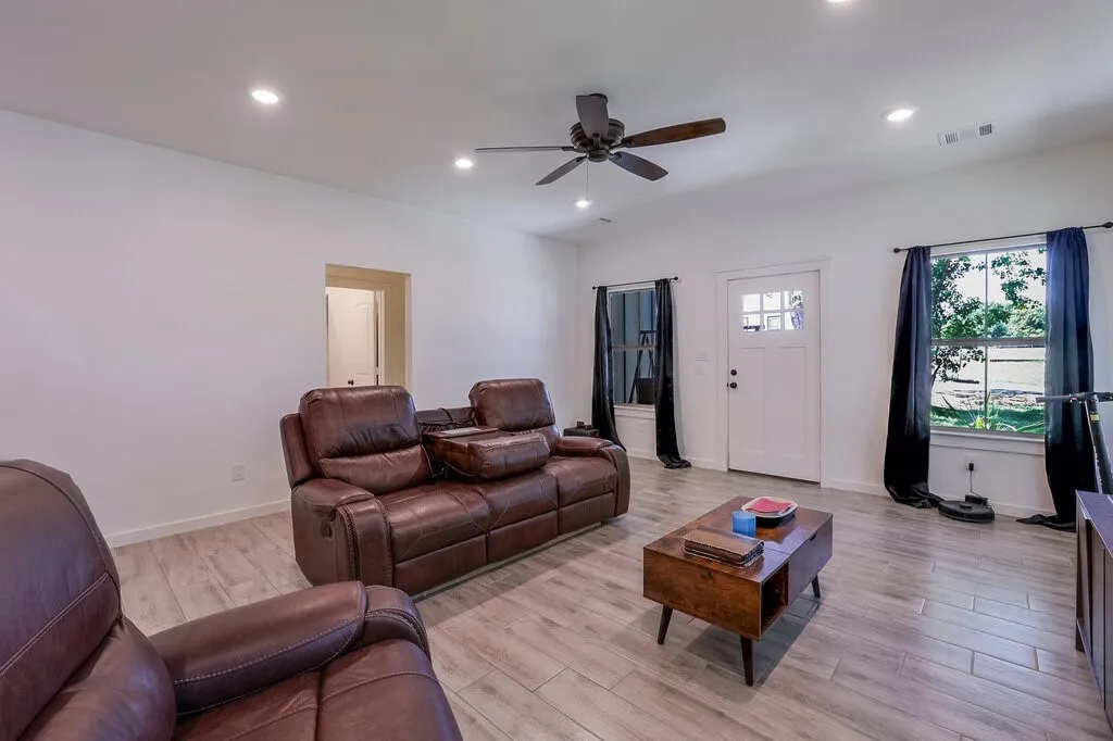 Recessed lighting, ceiling fan, wood-finish flooring, white paneled door, and multiple windows