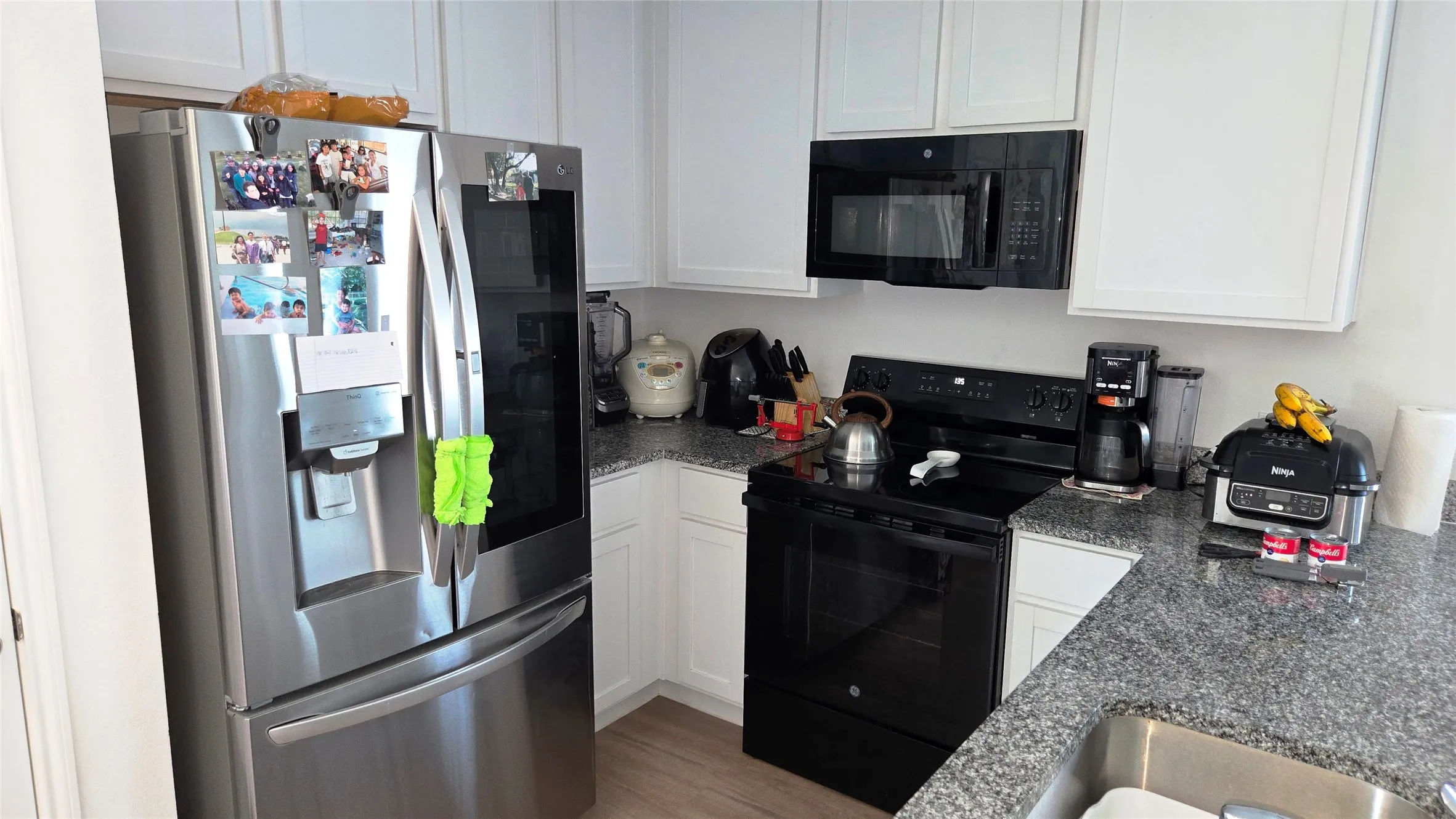 Modern kitchen featuring white cabinetry, granite-finish countertops, and wood-finish flooring
