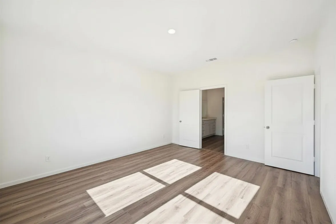 Recessed ceiling lighting, wood-finish flooring, white walls, white interior doors, and a pocket door