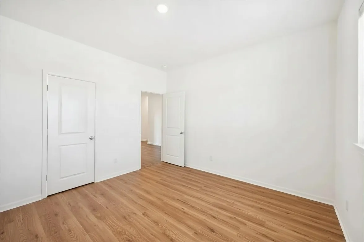 Wood-finish flooring, white walls, white doors, and a recessed ceiling light