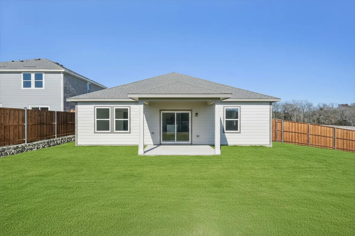 Expansive backyard with a covered patio, sliding glass door, and privacy fencing