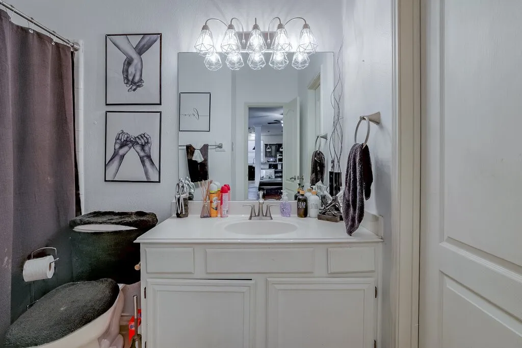 White vanity with shaker-style cabinetry, single integrated sink, and wall-mounted light fixture