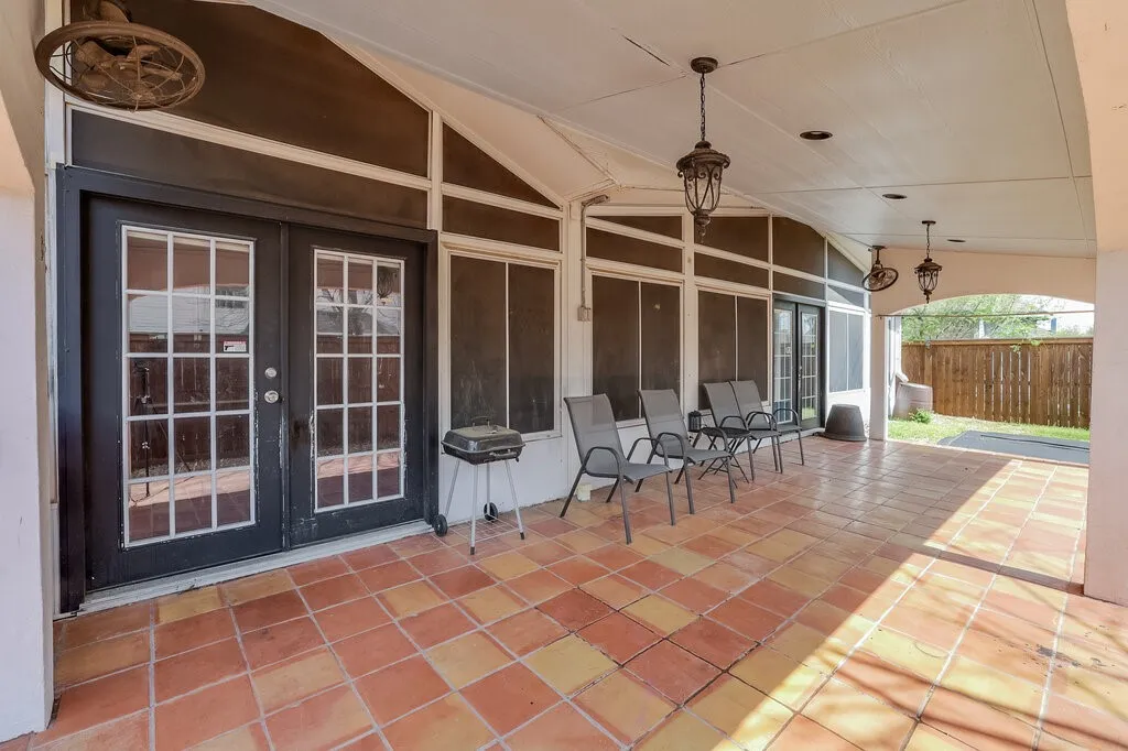 Covered patio featuring terra cotta tile flooring, multiple ceiling-mounted light fixtures, and a white arched support