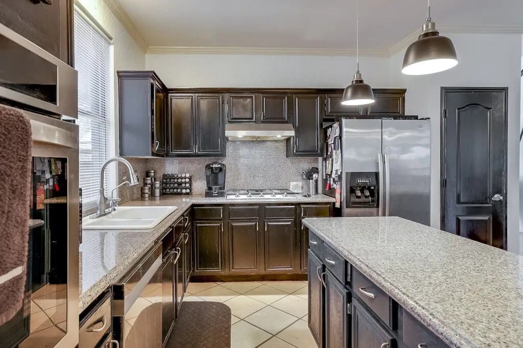 Kitchen featuring dark wood cabinetry, light-toned countertops, stainless steel appliances, and tile flooring