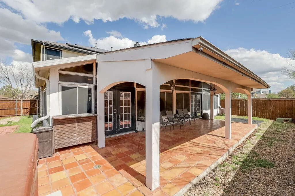 Covered patio with terracotta tile flooring, archways, and multiple access doors