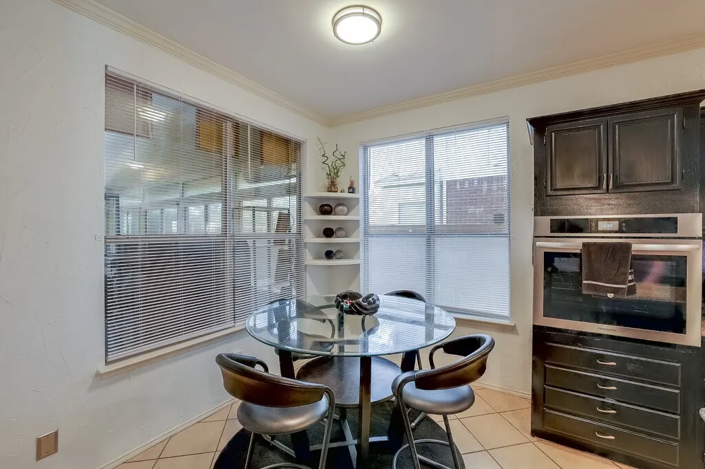 Built-in stainless steel oven, dark wood cabinetry, crown molding, round ceiling light fixture, and corner shelving unit