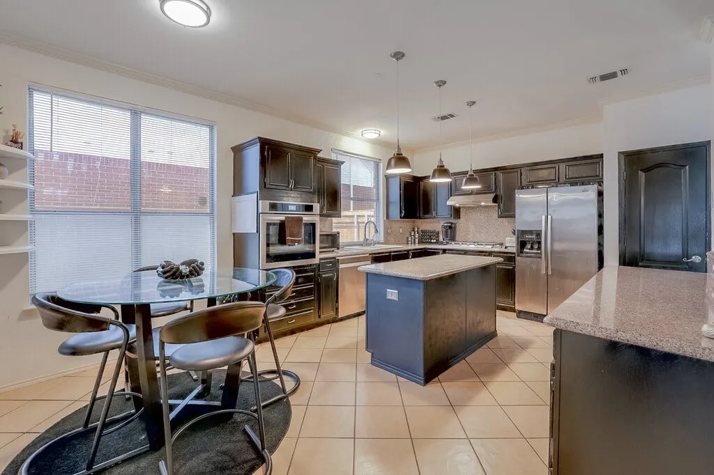 Spacious kitchen featuring dark cabinetry, stainless steel appliances, a center island with countertop, and tile flooring