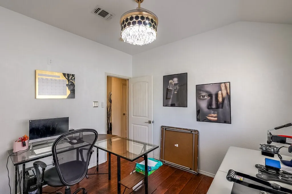 Wood-finish flooring, white walls, and a crystal chandelier fixture