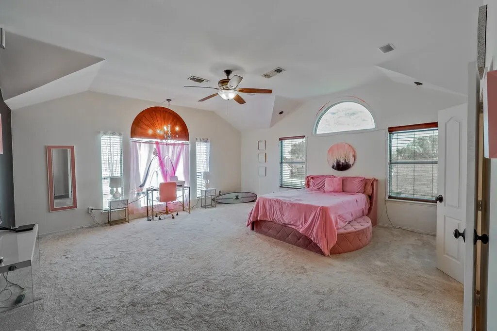 Vaulted ceilings, arched window, recessed lighting, ceiling fan, and light-toned carpeting