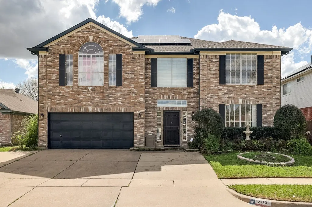 Brick exterior with gabled roofline, solar panels, attached garage, and a concrete driveway