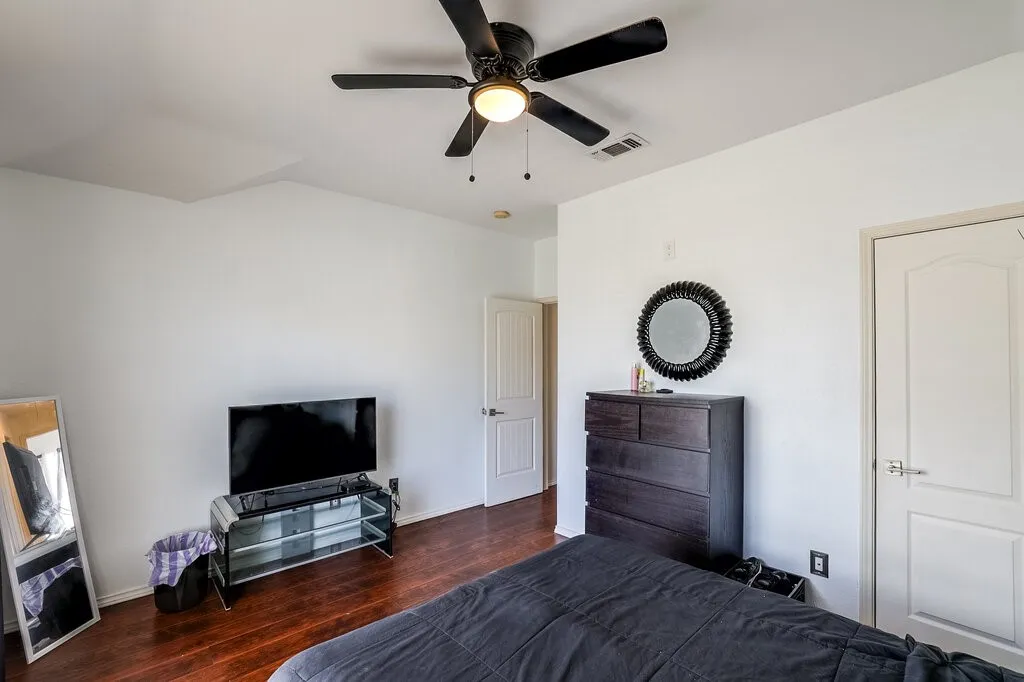 Wood-finish flooring with white walls and a ceiling fan
