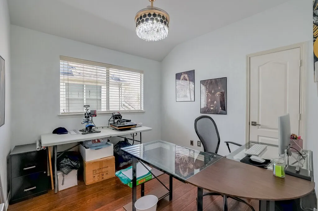 Room with wood-finish flooring, a contemporary crystal chandelier, and a window with horizontal blinds