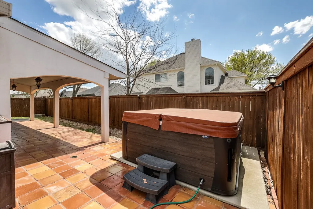 Outdoor patio featuring a covered area, terracotta-style pavers, and a built-in hot tub
