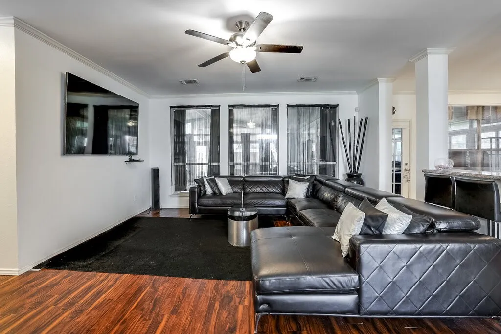 Warm wood-finish flooring, recessed lighting, and a ceiling fan with integrated lighting