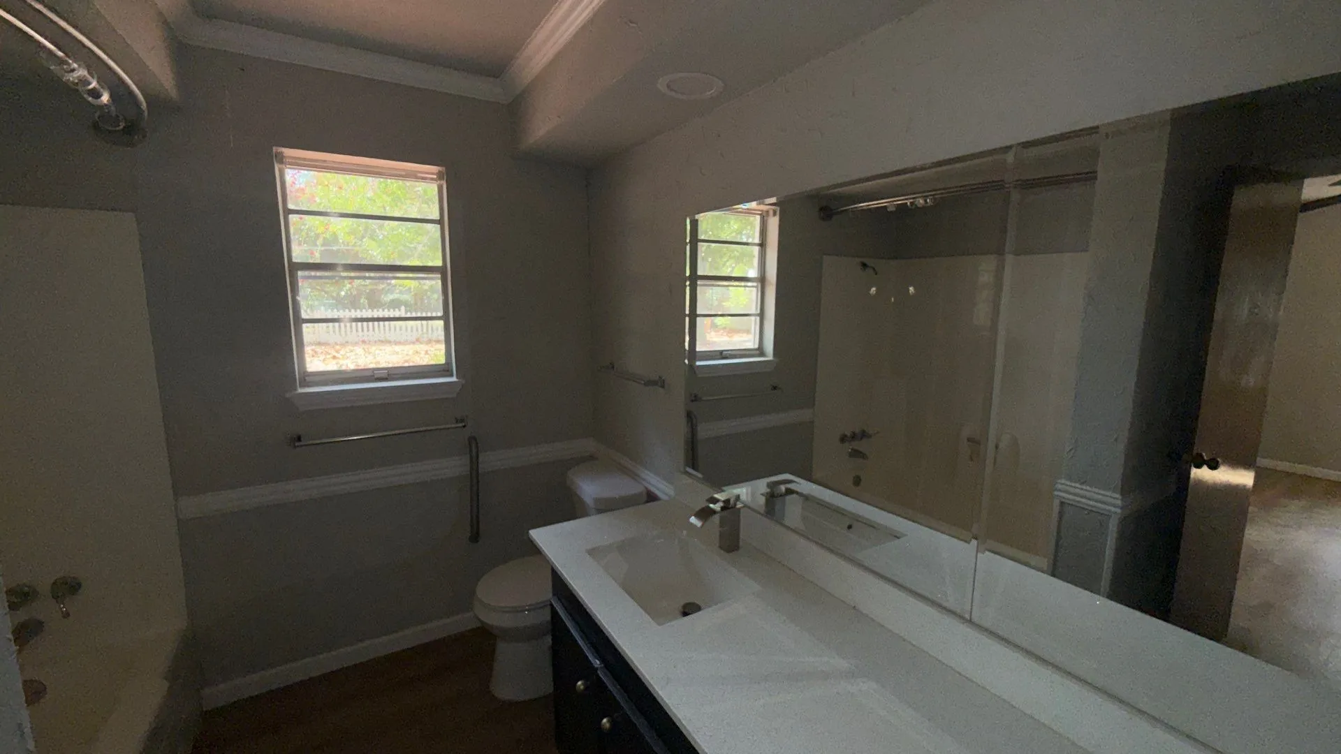 Bathroom featuring a single vanity with an integrated sink, large wall-mounted mirror, and a combination tub/shower