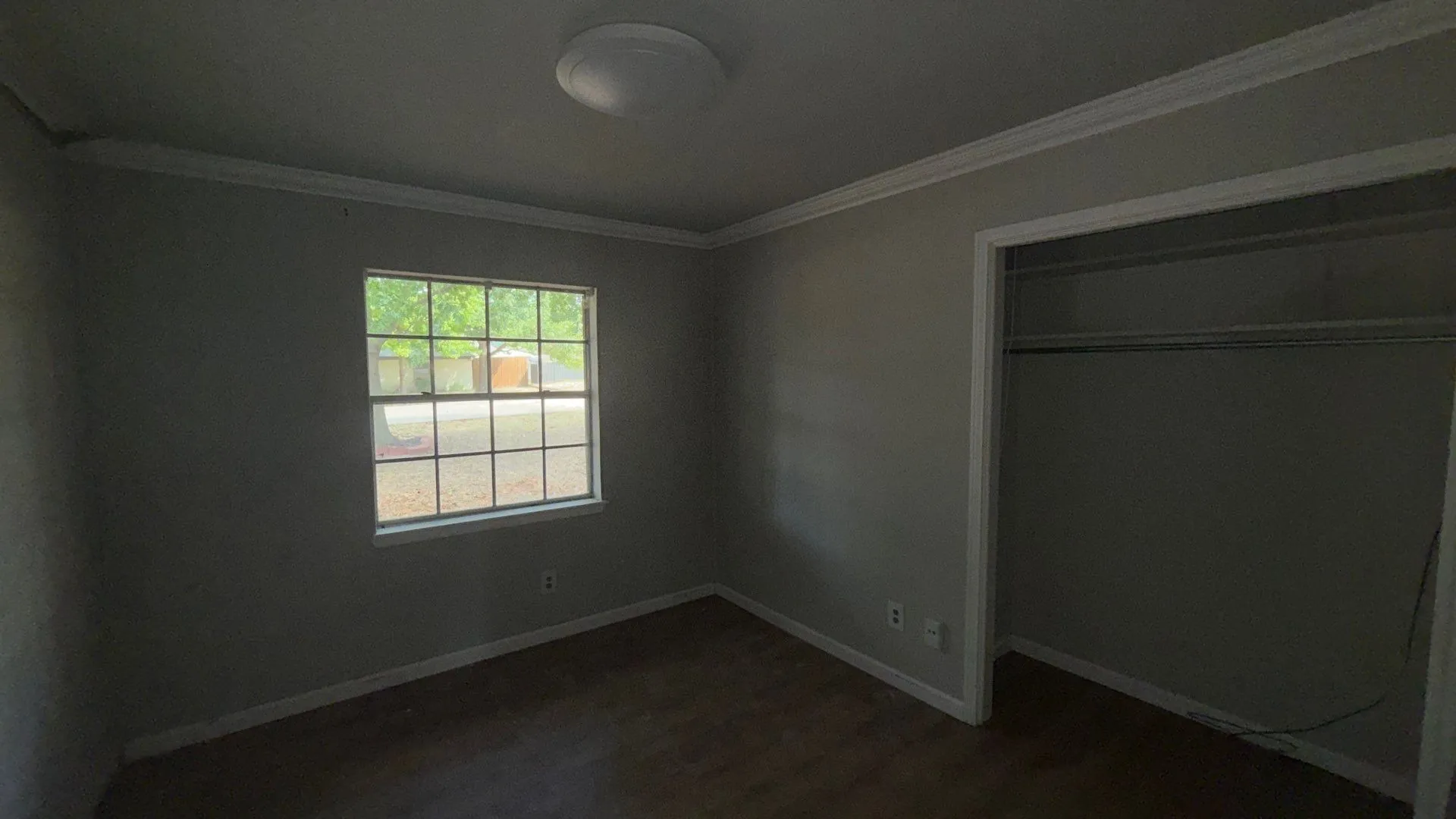 Neutral wall tones, wood-finish flooring, crown molding, and an open closet with wire shelving