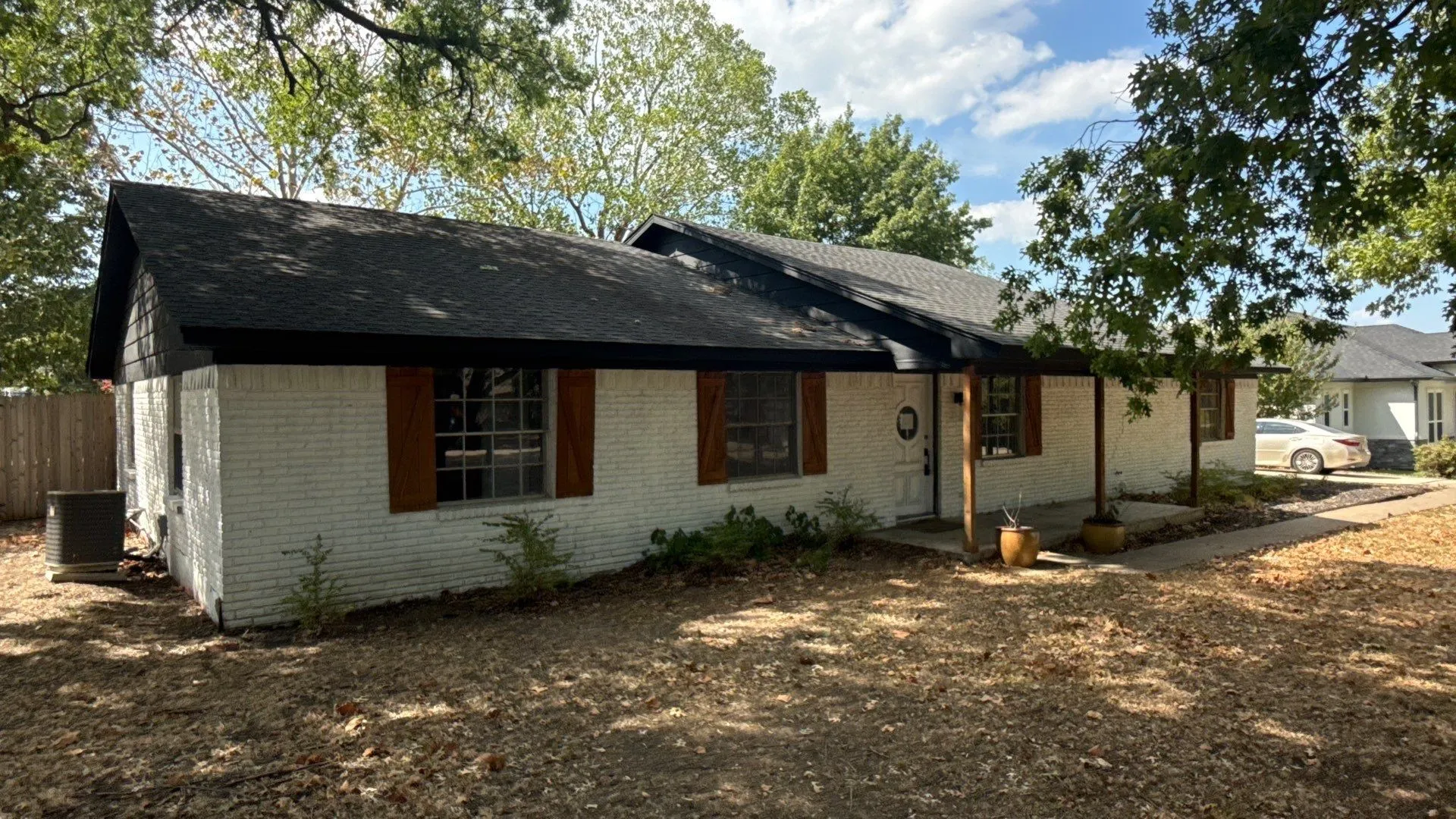 White painted brick exterior with a black shingle roof