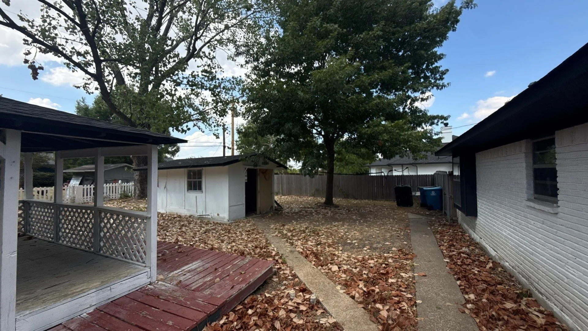 Expansive backyard featuring a covered patio with lattice railing, a detached storage shed, and a concrete pathway