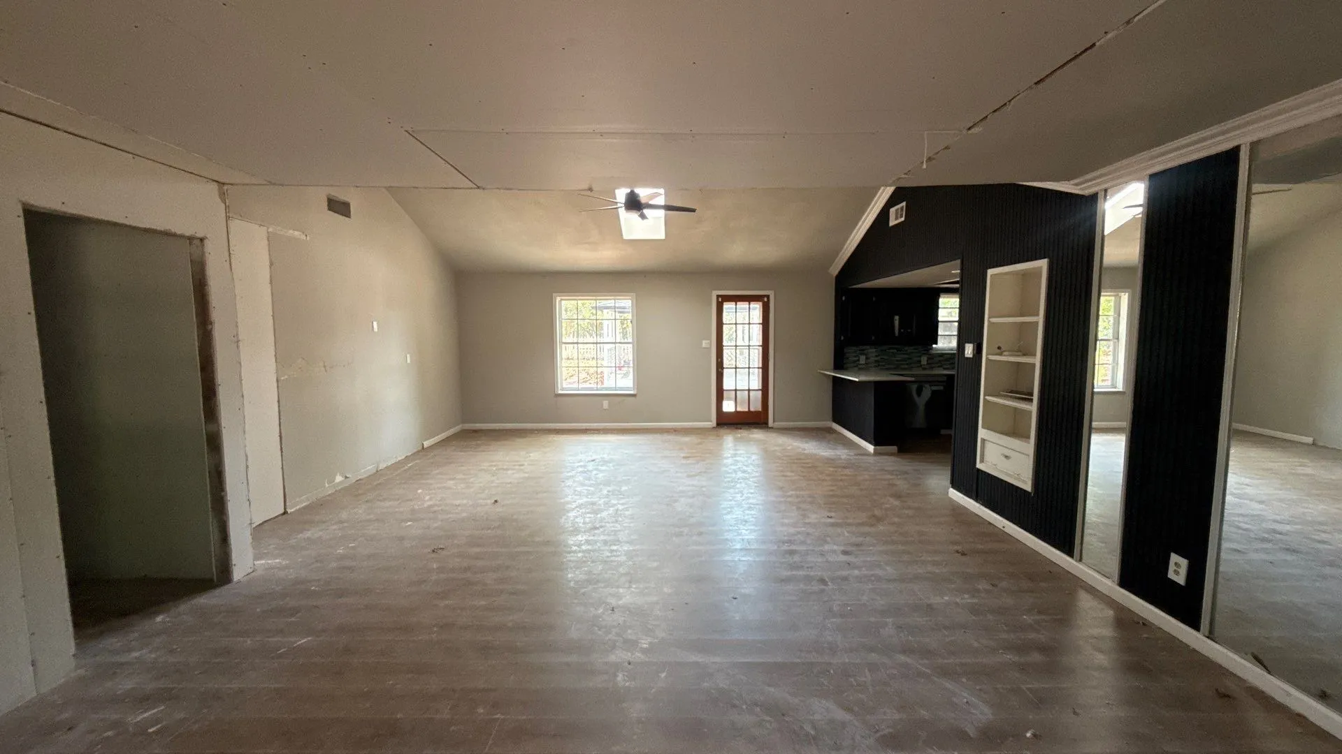 Vaulted ceiling with skylight, wood-finish flooring, built-in shelving, dark cabinetry, and a glass-paned door