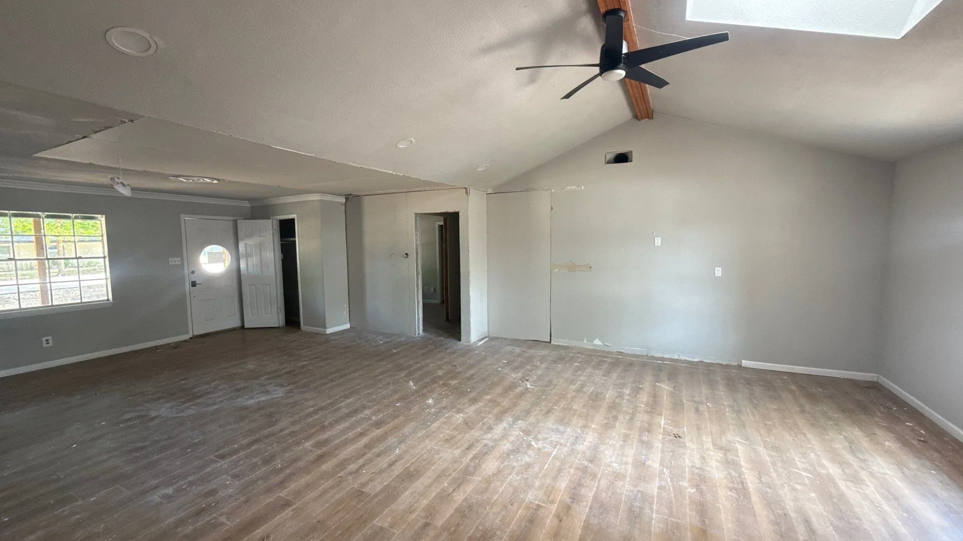 Vaulted ceiling with exposed wood beam, skylight, and ceiling fan