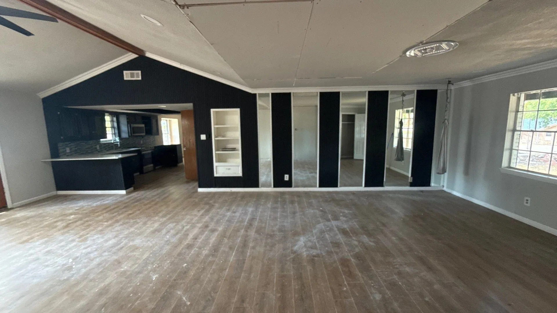 Wood-finish flooring throughout, with a built-in shelving unit, and a mirrored wall feature