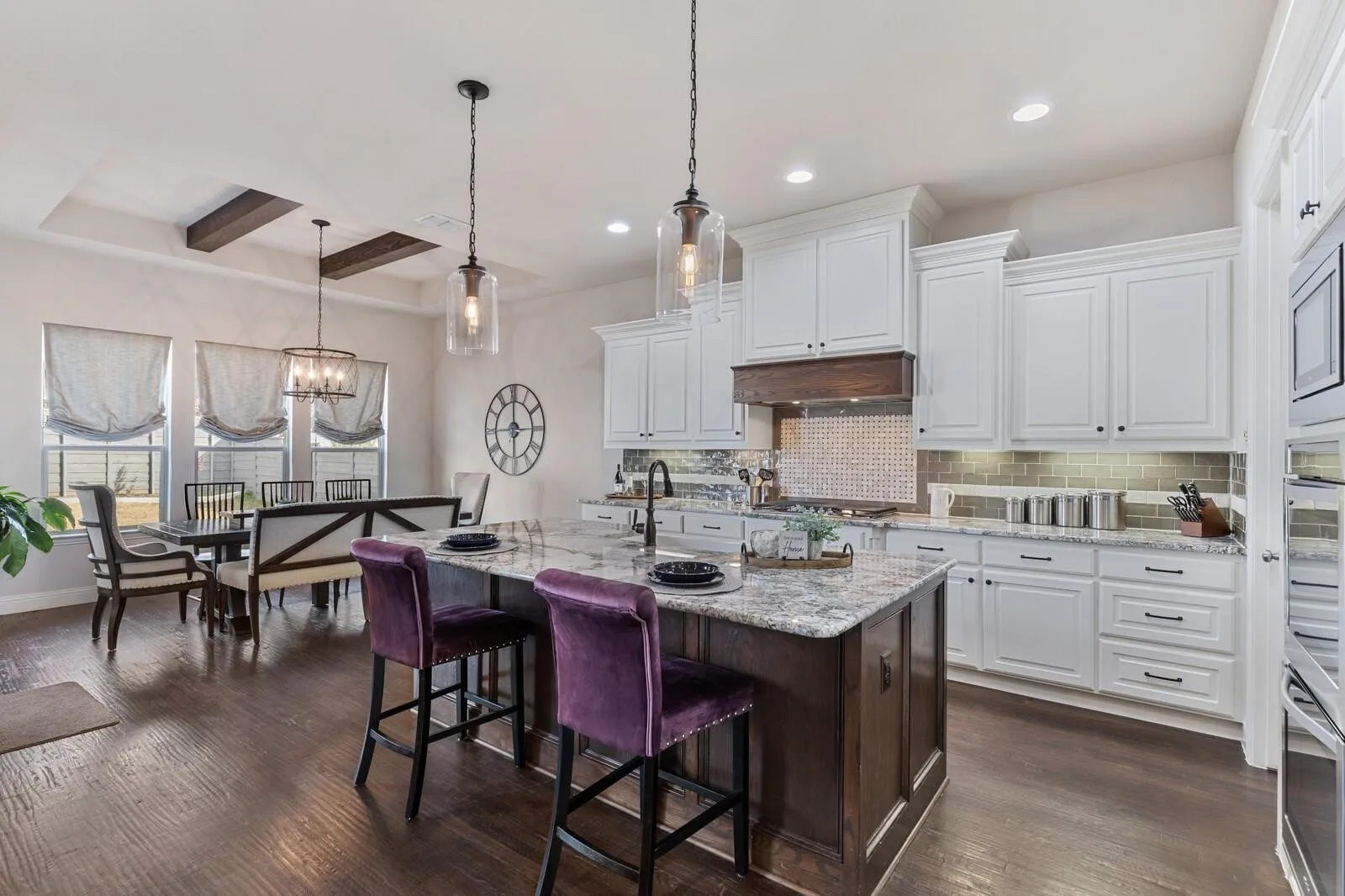 Gourmet kitchen featuring white cabinetry, a center island with dark wood base and purple upholstered seating, stainless steel appliances, subway tile backsplash, and quartz countertops