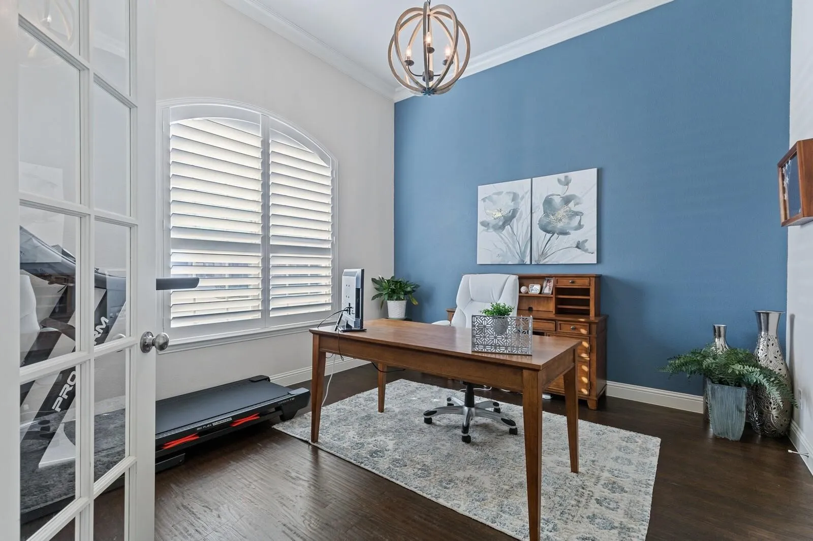 French doors, arched window with plantation shutters, wood-finish flooring, crown molding, and a spherical chandelier