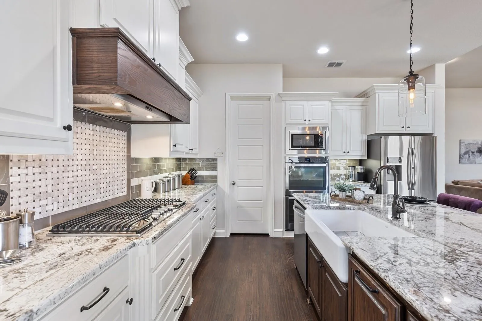 Gourmet kitchen with white cabinetry, granite countertops, stainless steel appliances, and a farmhouse sink