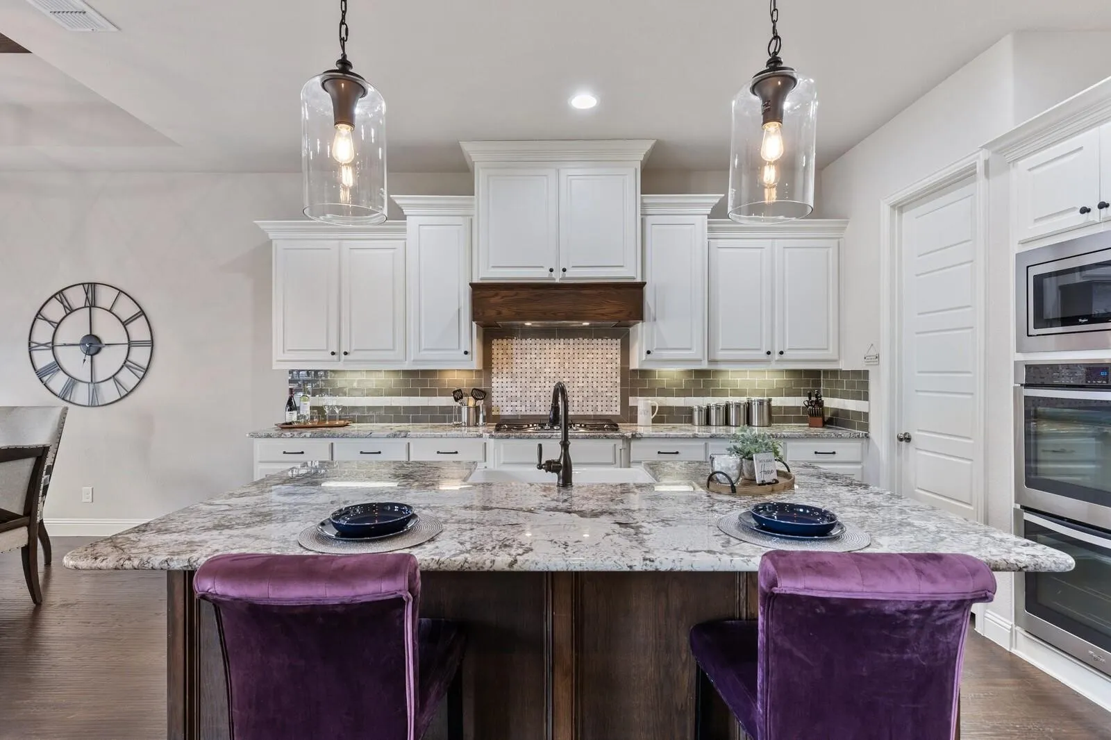 Gourmet kitchen featuring white cabinetry, quartz countertops, stainless steel appliances, and a large island with seating for multiple guests