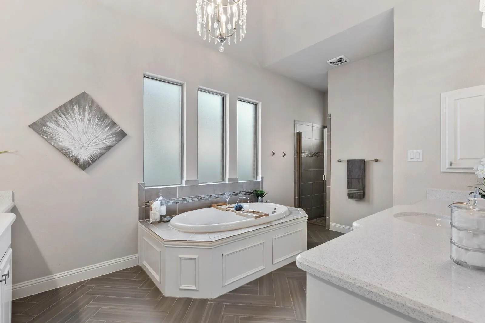 Soaking tub with tiled surround, three transom windows, and herringbone pattern tile flooring
