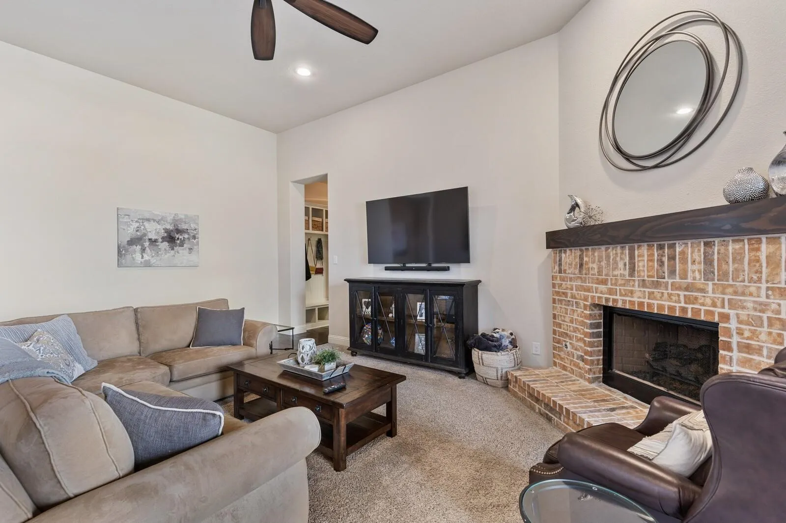 Spacious living room anchored by a wood-burning fireplace with exposed brick surround and mantel display space