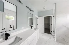 Dual vanity with white cabinetry and countertops, matte black fixtures, rectangular mirrors, and a glass-enclosed shower