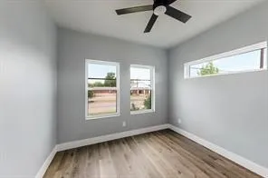 Wood-finish flooring, white trim, dual windows, transom window, and a ceiling fan