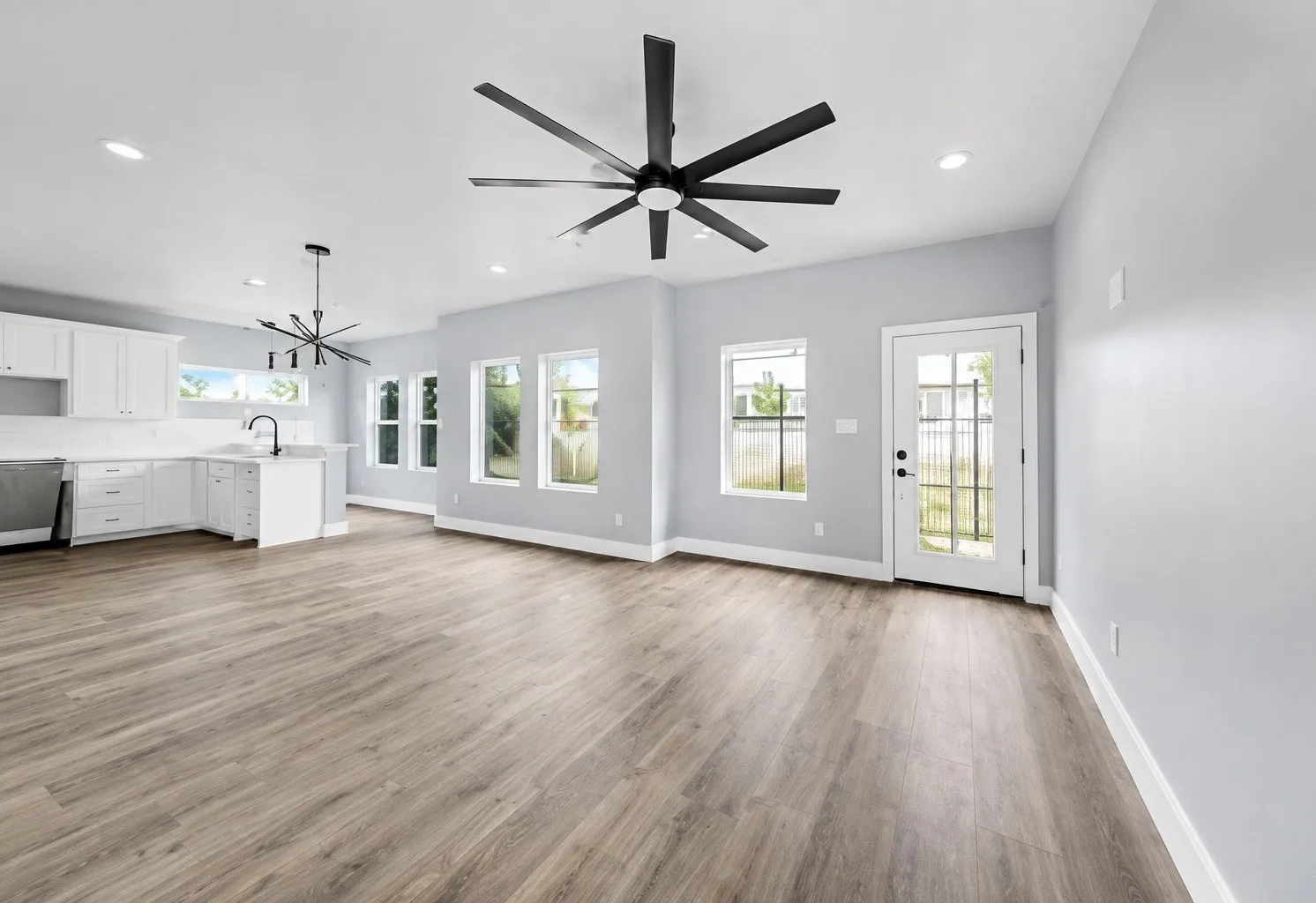 Open-concept living area with wood-finish flooring, recessed lighting, and a modern ceiling fan