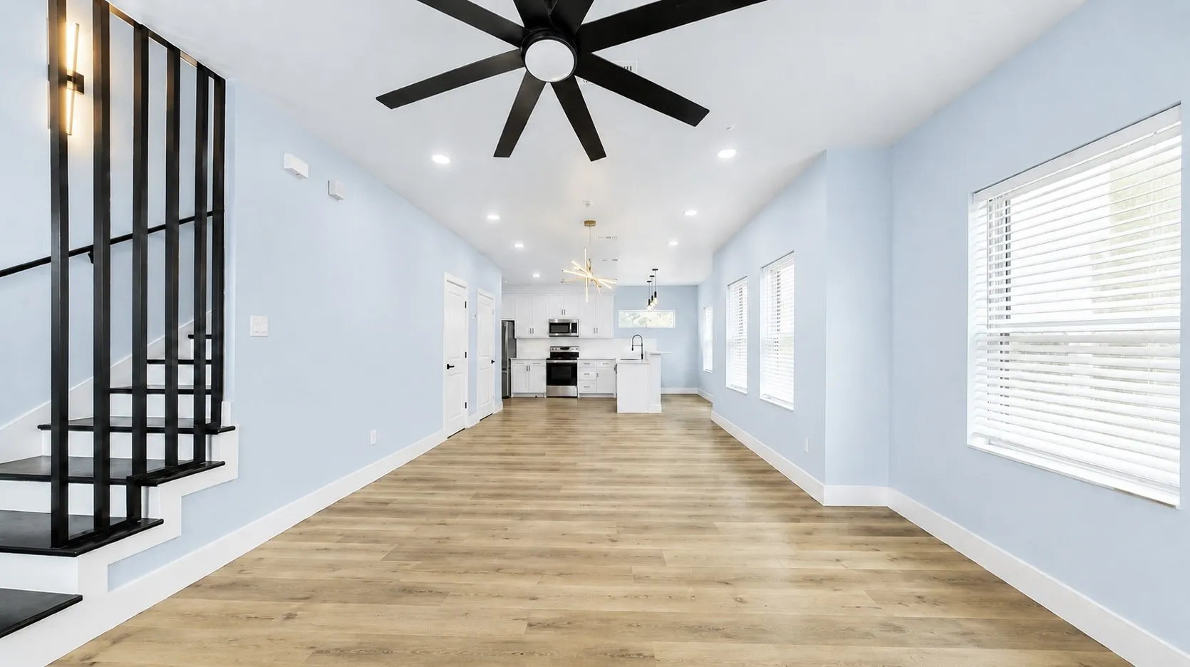 Open-concept living area with wood-finish flooring, recessed lighting, and multiple windows