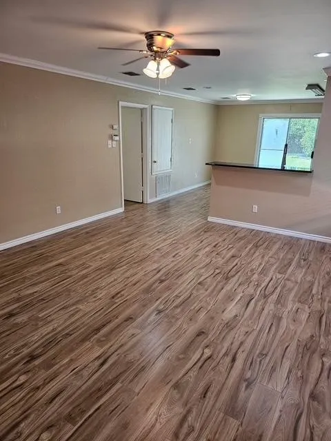 Unfurnished room featuring crown molding, wood finished floors, and a ceiling fan