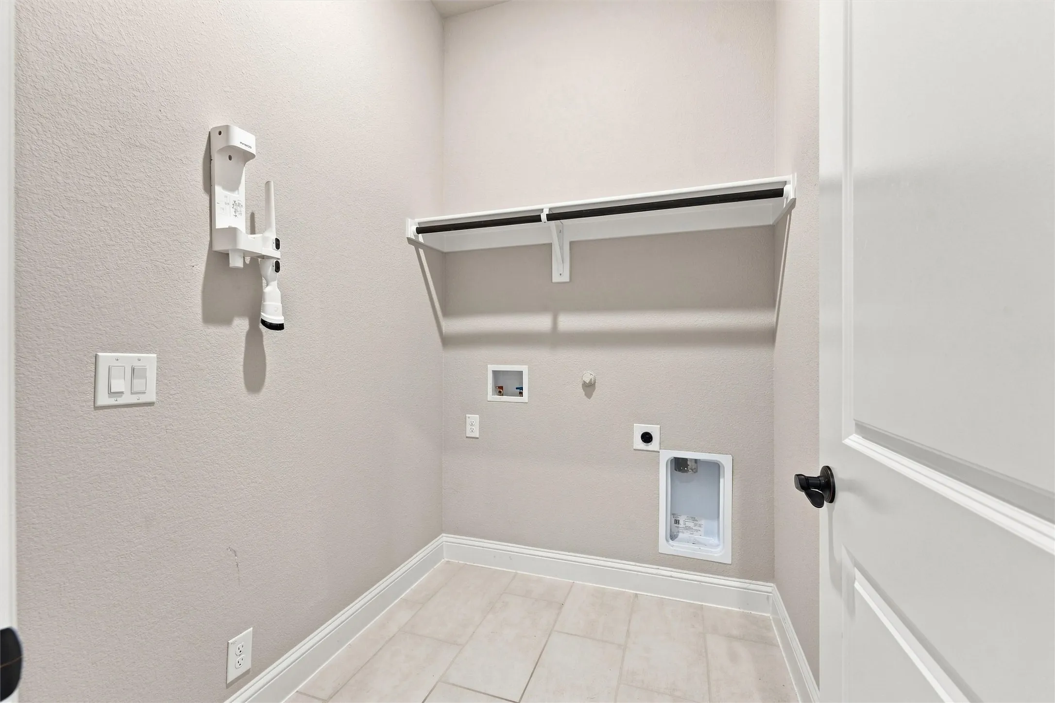 Light-toned tile flooring, light-colored walls, and a built-in shelf with a hanging rod