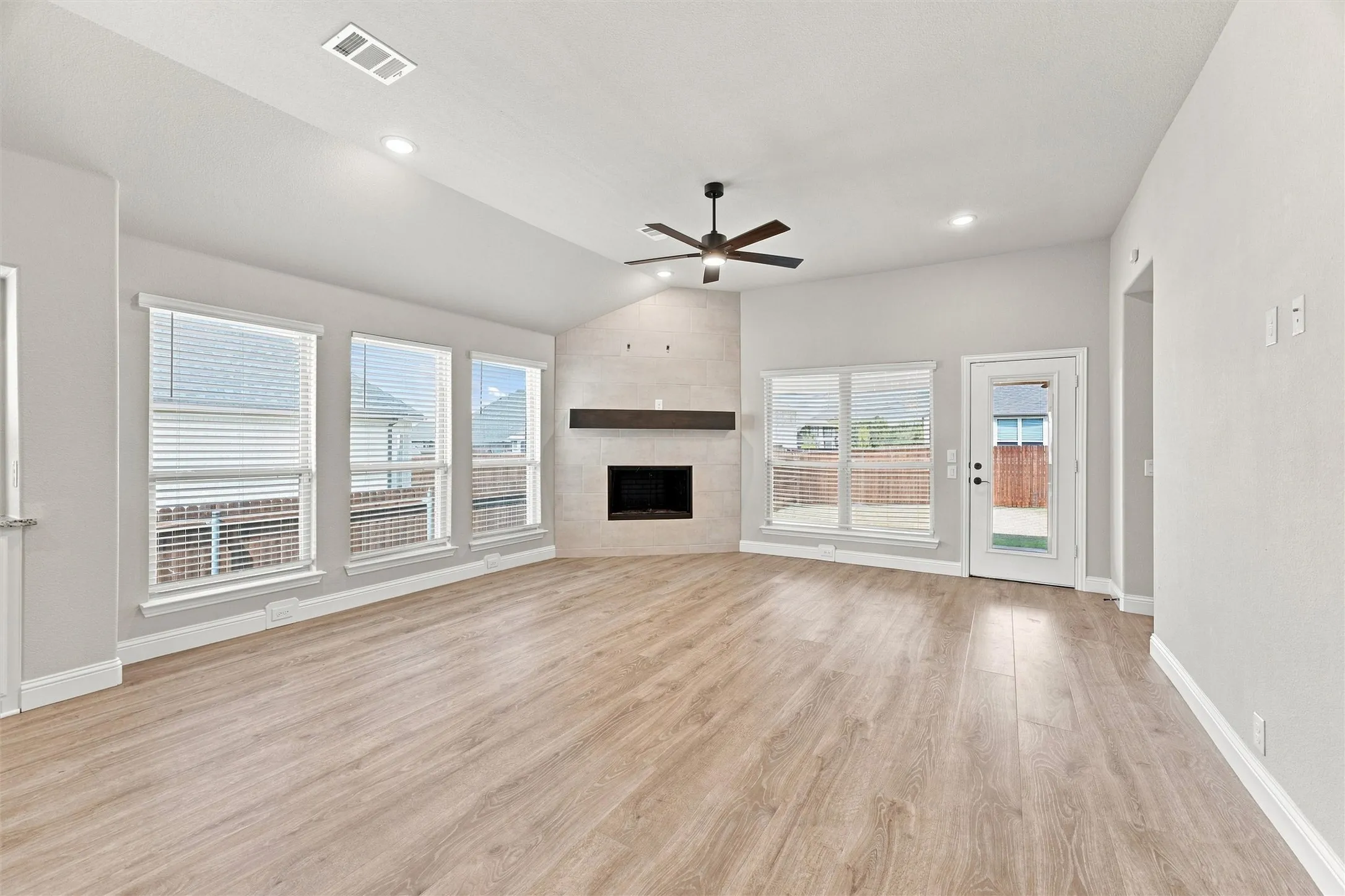Spacious open-concept living area featuring wood-finish flooring throughout, recessed ceiling lighting, and a ceiling fan
