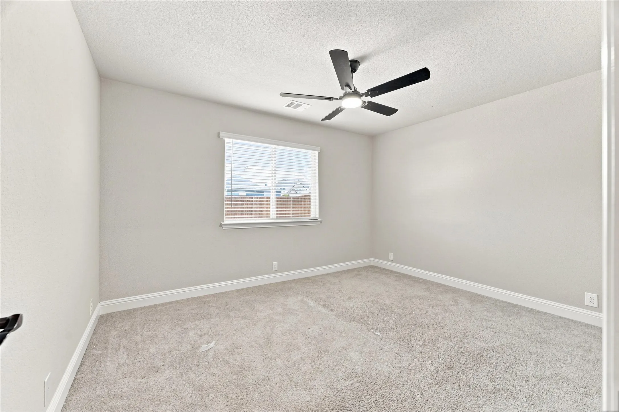 Neutral tone wall paint, carpeted flooring, window with blinds, and ceiling fan with integrated lighting
