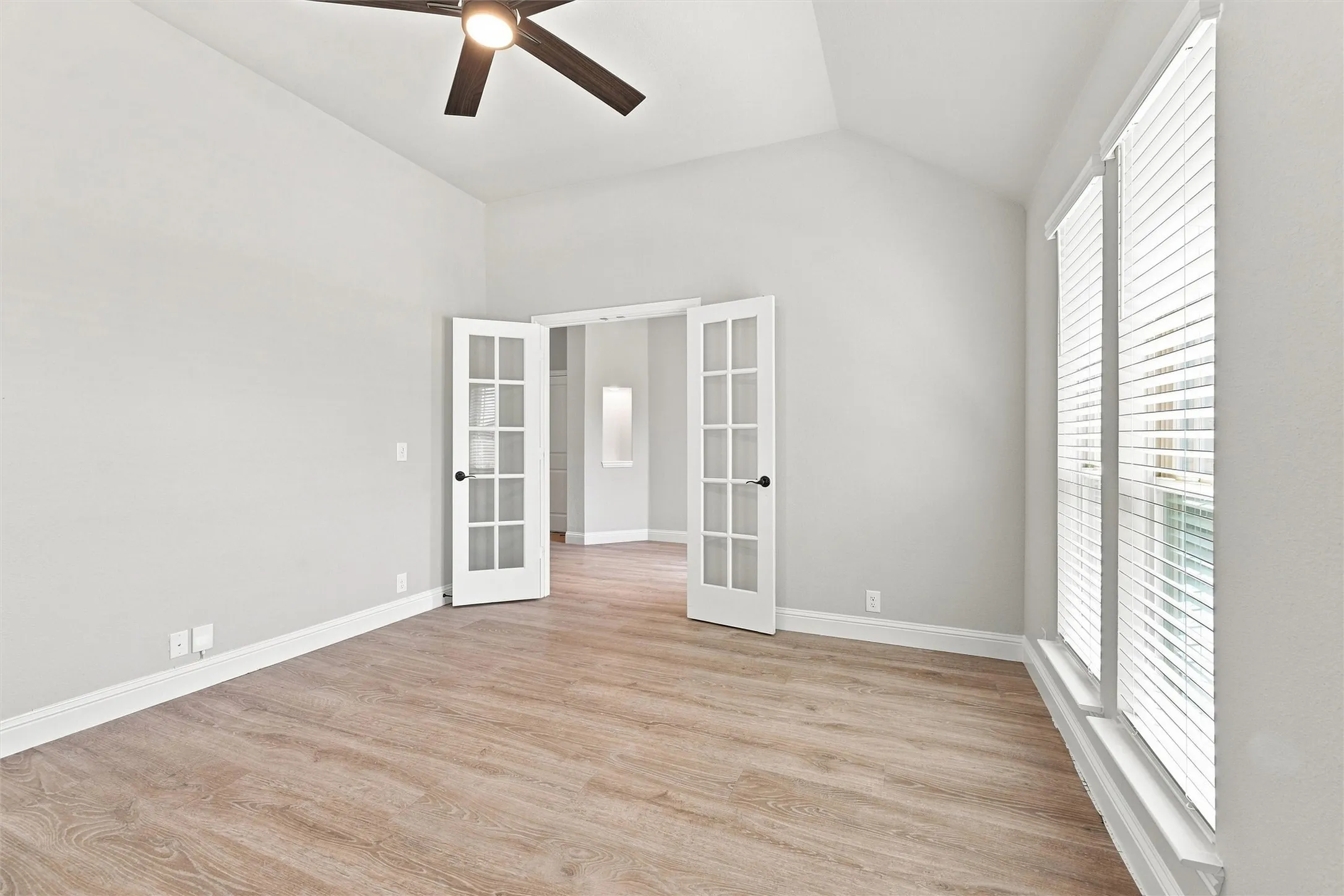 Vaulted ceiling with a ceiling fan, wood-finish flooring, and double French doors